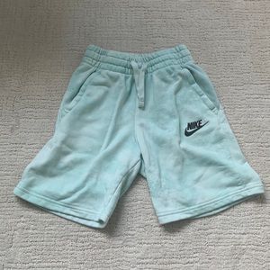 A pair of teal youth medium Nike shorts with heat reactive logo.